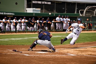 scott roeder | Staff Photographer Jeff Cusick slides into home plate safely as the ball bounces off Fullerton catcher Billy Marcoe’s shoulder.