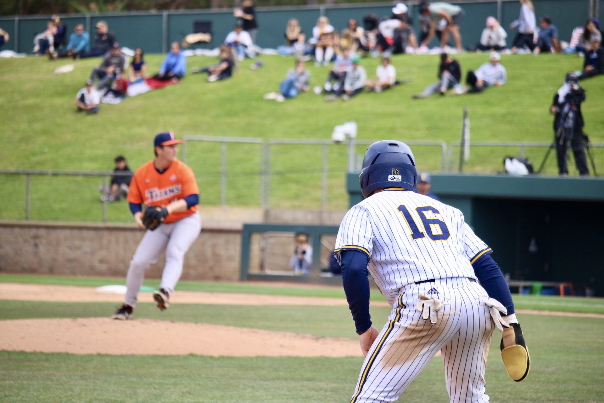 A UC Irvine base runner watches a Califonia State University, Fullerton pitcher throw