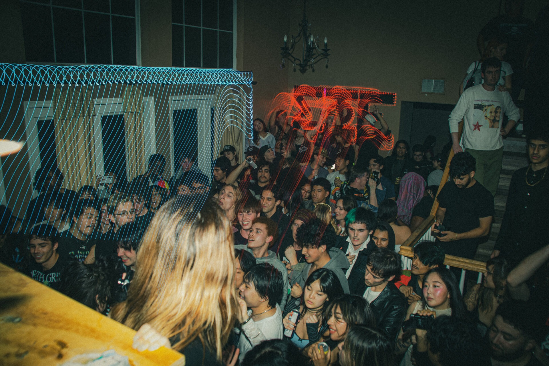 A large group of young adults crowd together inside the Sigma Phi Epsilon fraternity house during a rave organized by Irvine Drainers.