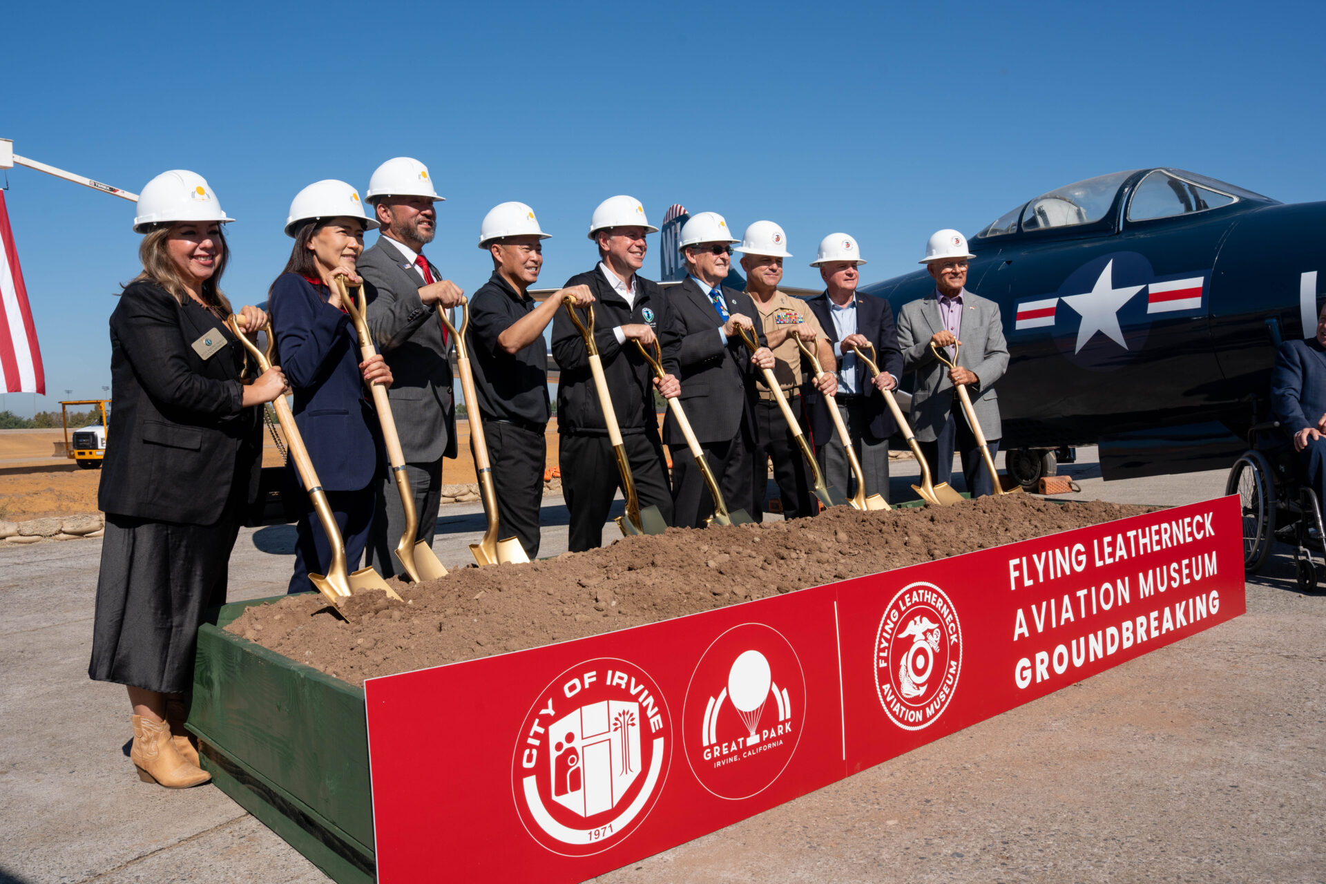 City officials Irvine officials, Marine Corps representatives and members of the Flying Leatherneck Historical Foundation stand together in a line and pose with shovels at the groundbreaking site.