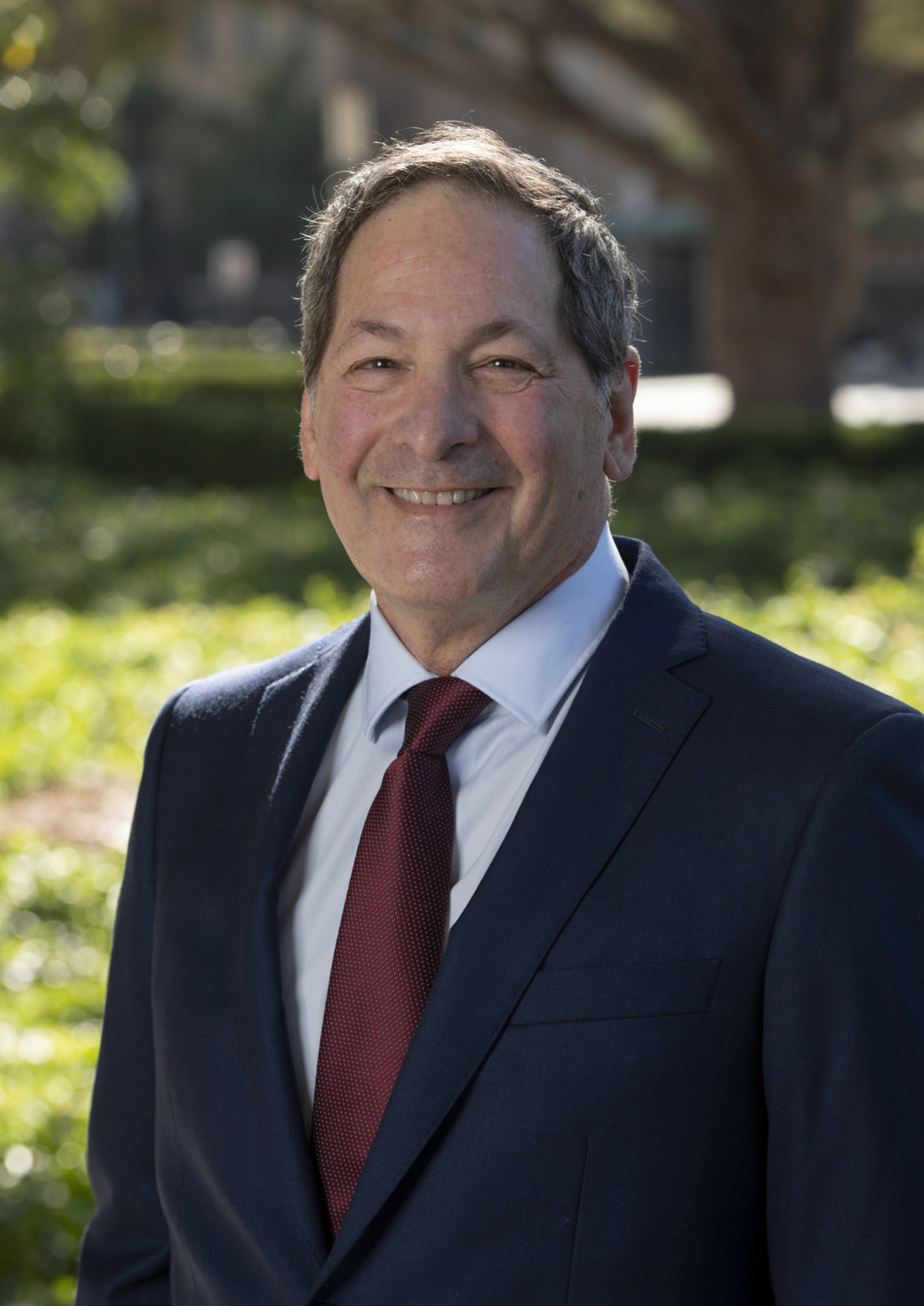 A photo of Michael Leon smiling against a background of trees and grass.