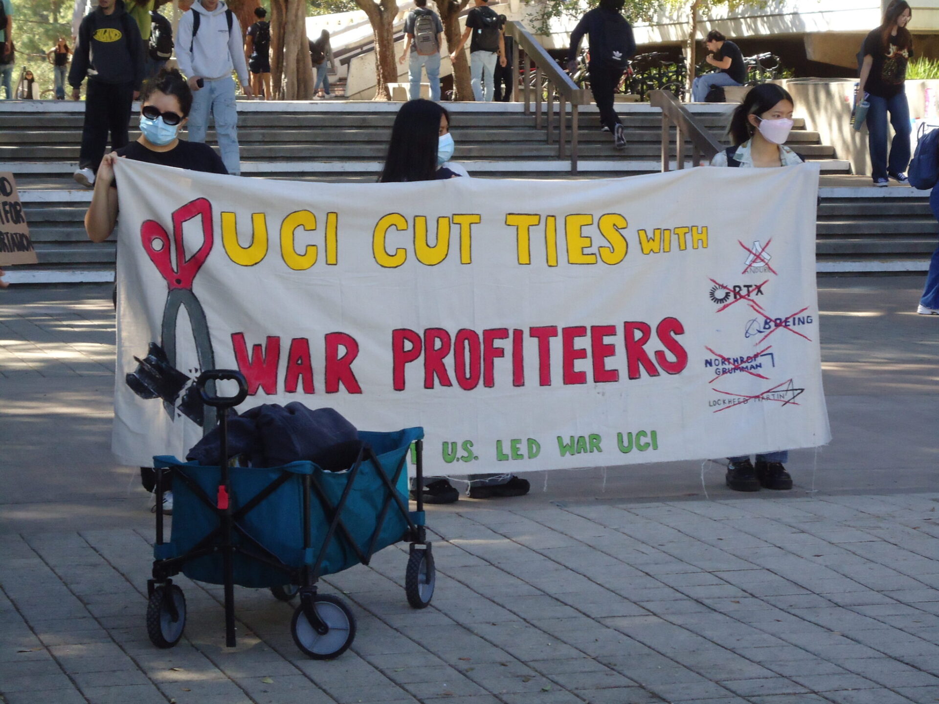 Three UCI students hold up a sign that reads 
