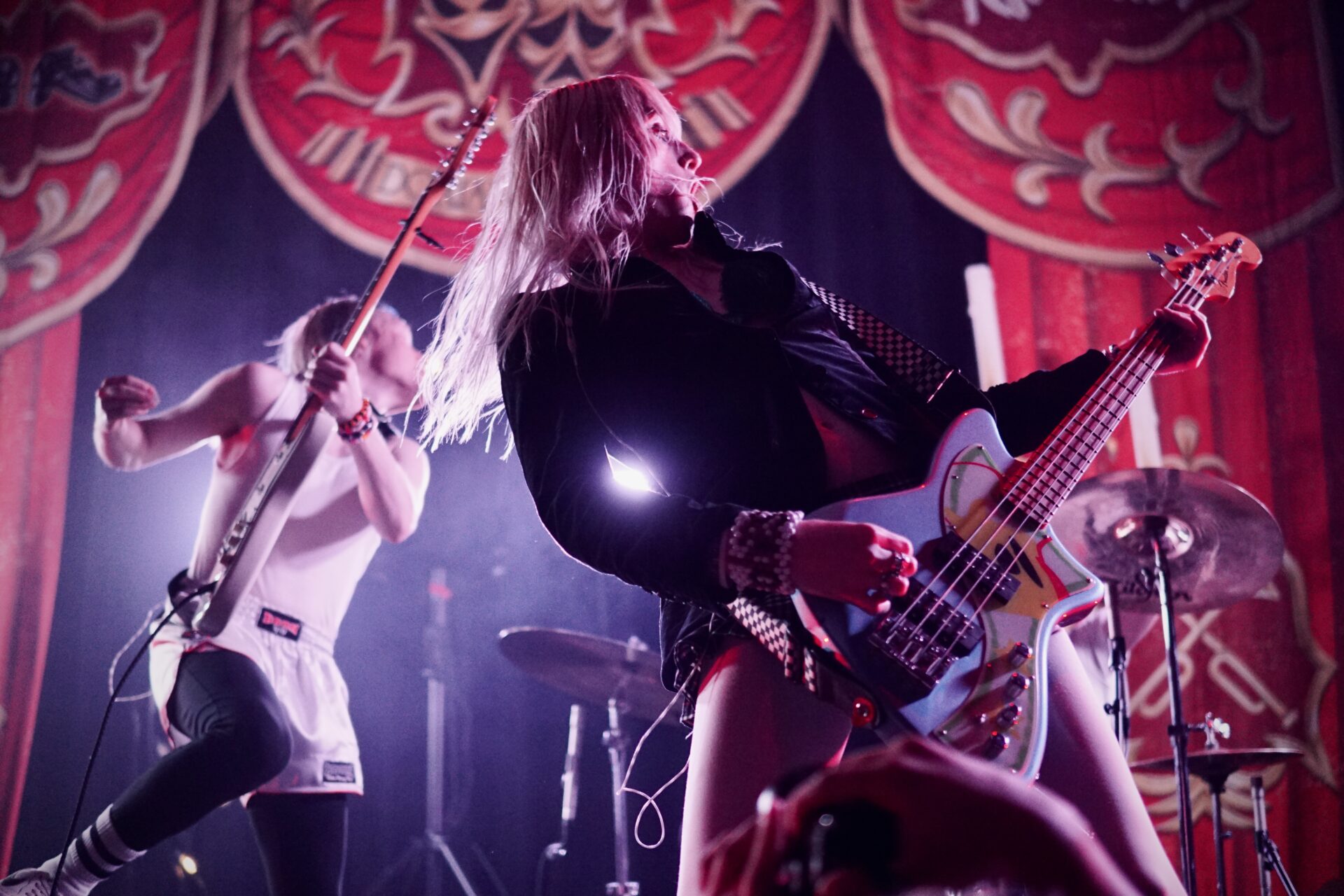 Frost Children performing at the Hollywood Theater in Vancouver, with Angel playing a guitar in the front on the right and Lulu playing a guitar behind her on the left.
