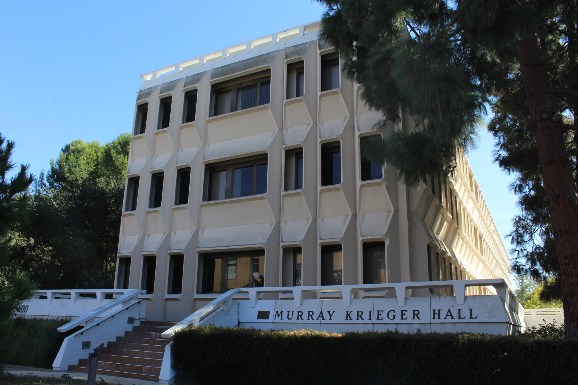 A close up photo of Murray Krieger Hall surrounded by trees on a sunny day.