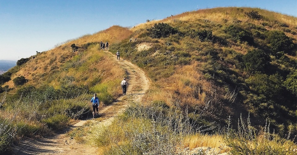 Six hikers are shown walking up a trail in Irvine, California.