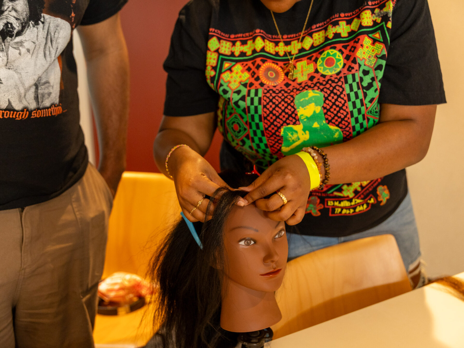 A participant of UCI's Black Hair Care and Wellness (BCHW) event, braiding a mannequin's hair.