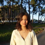 Sara Khan smiles in front of trees on the UCI campus
