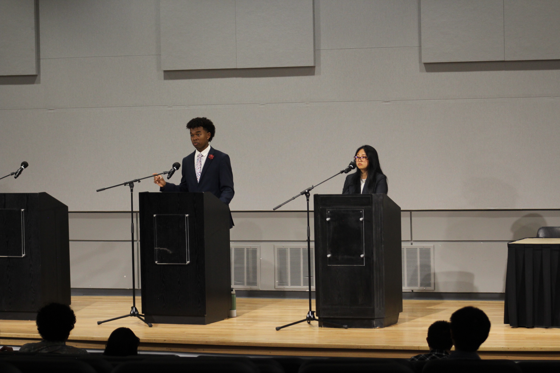 Long shot of the debating floor. Both candidates are ready at the mic to speak on their turn.