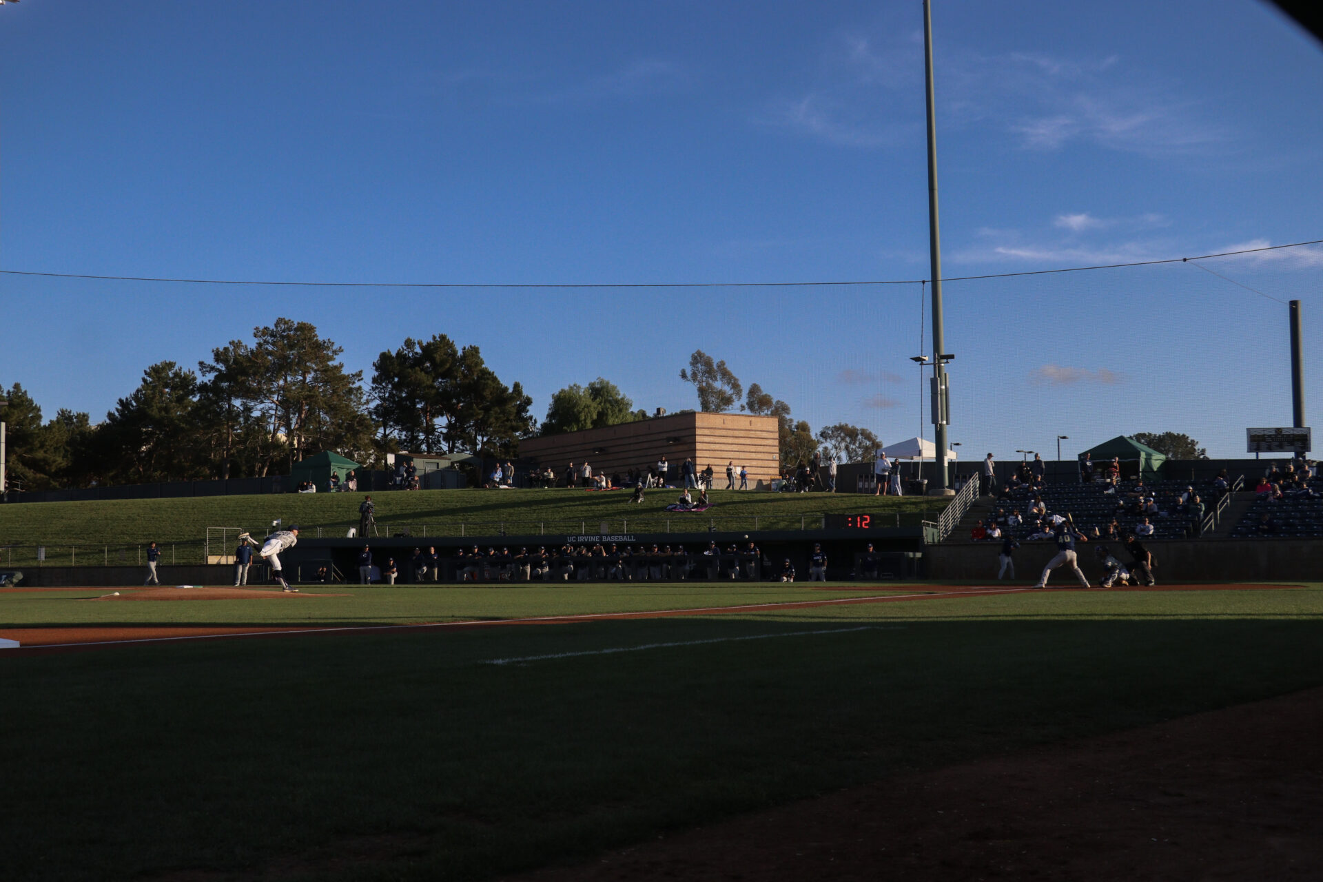 UC Irvine player number twenty eight, Trevor Hanson, kicks back leg as he pitches ball towards UC Davis player.