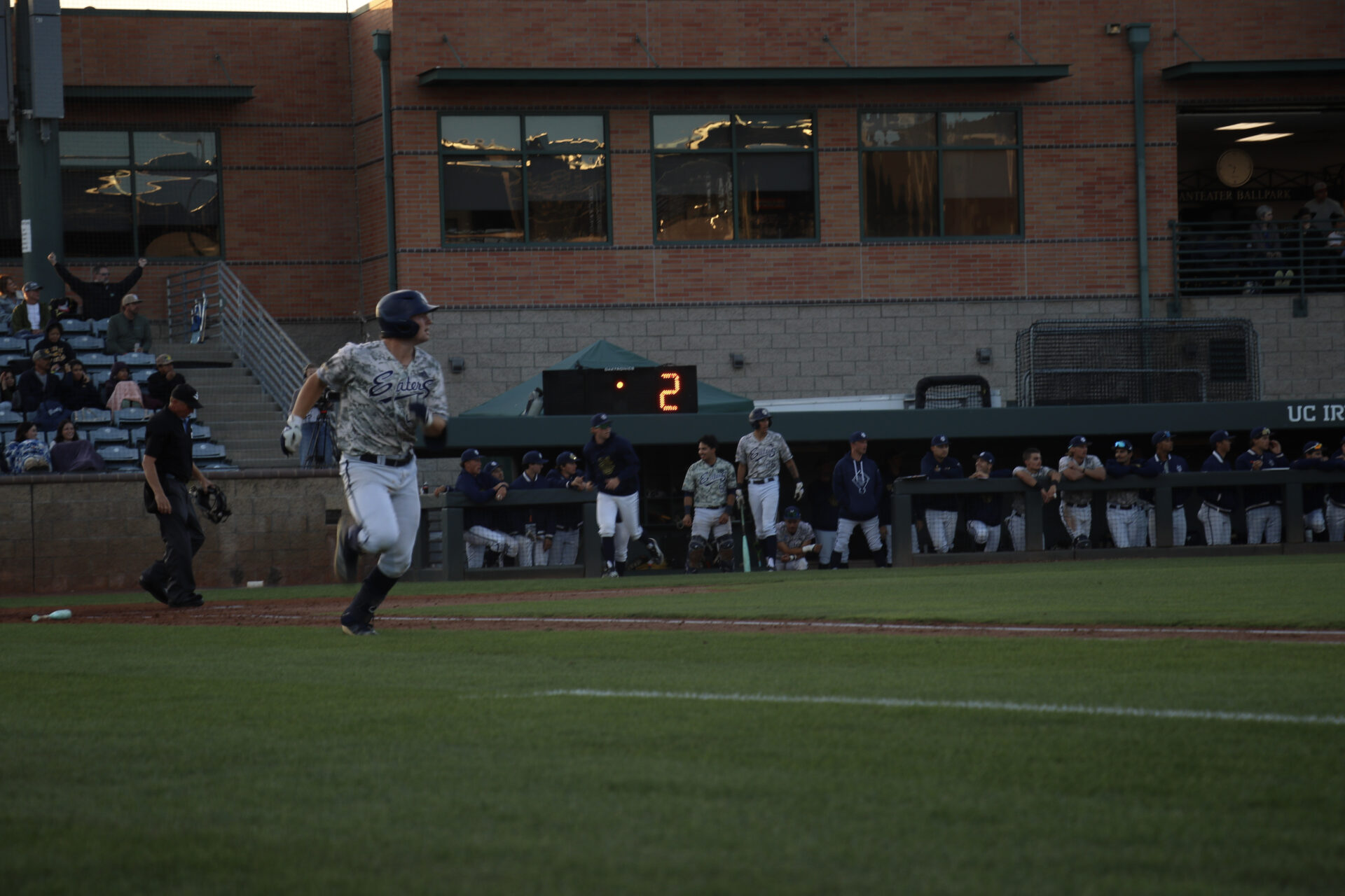 UC Irvine player number twenty four, Auggie Guitierrez, looks over left shoulder as he runs to first base after swinging the ball into center field.