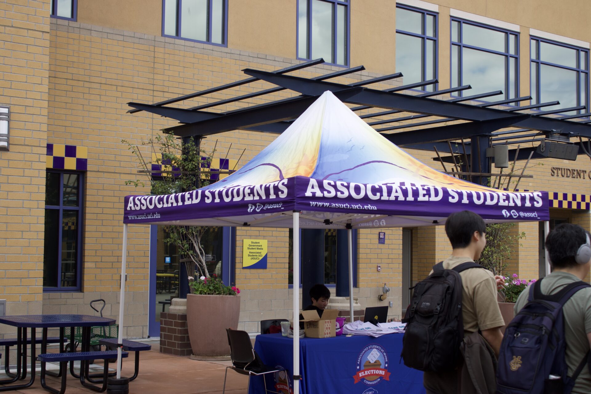 An ASUCI booth set up by the Elections Commission is shown. The booth stands in front of the ASUCI and SGSM office.