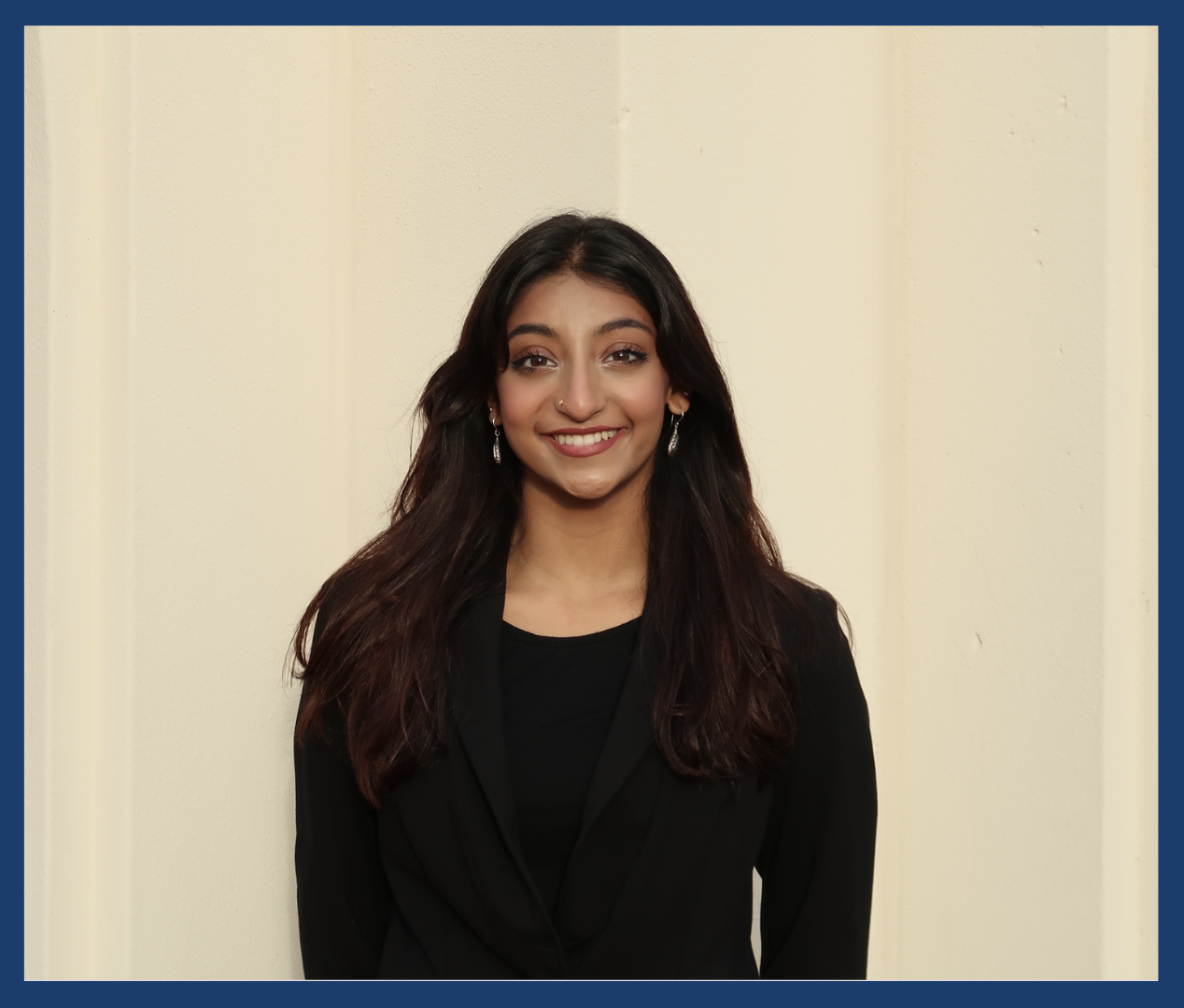 A photo of ASUCI Associate Vice President of Diversity, Equity and Inclusion candidate Neha Mahesh is shown. Mahesh stands in front of a white cream background dressed in all black.