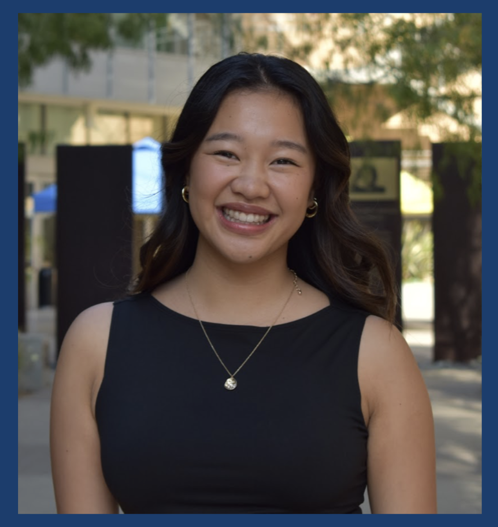 A photo of ASUCI Student Programming Commissioner candidate Sarah Gagnier is shown. Gagnier stands in front of an area at UCI campus and is wearing a black shirt.