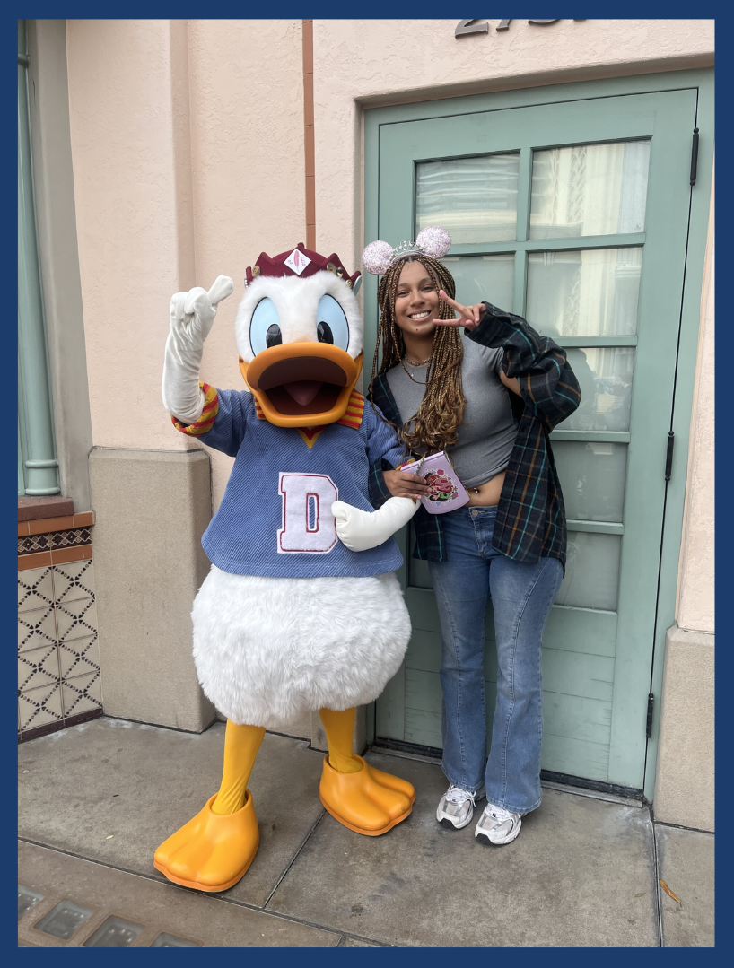 A photo of ASUCI Transfer Senator candidate Danellie McIntyre is shown. McIntyre stands next to Donald Duck from Disneyland.