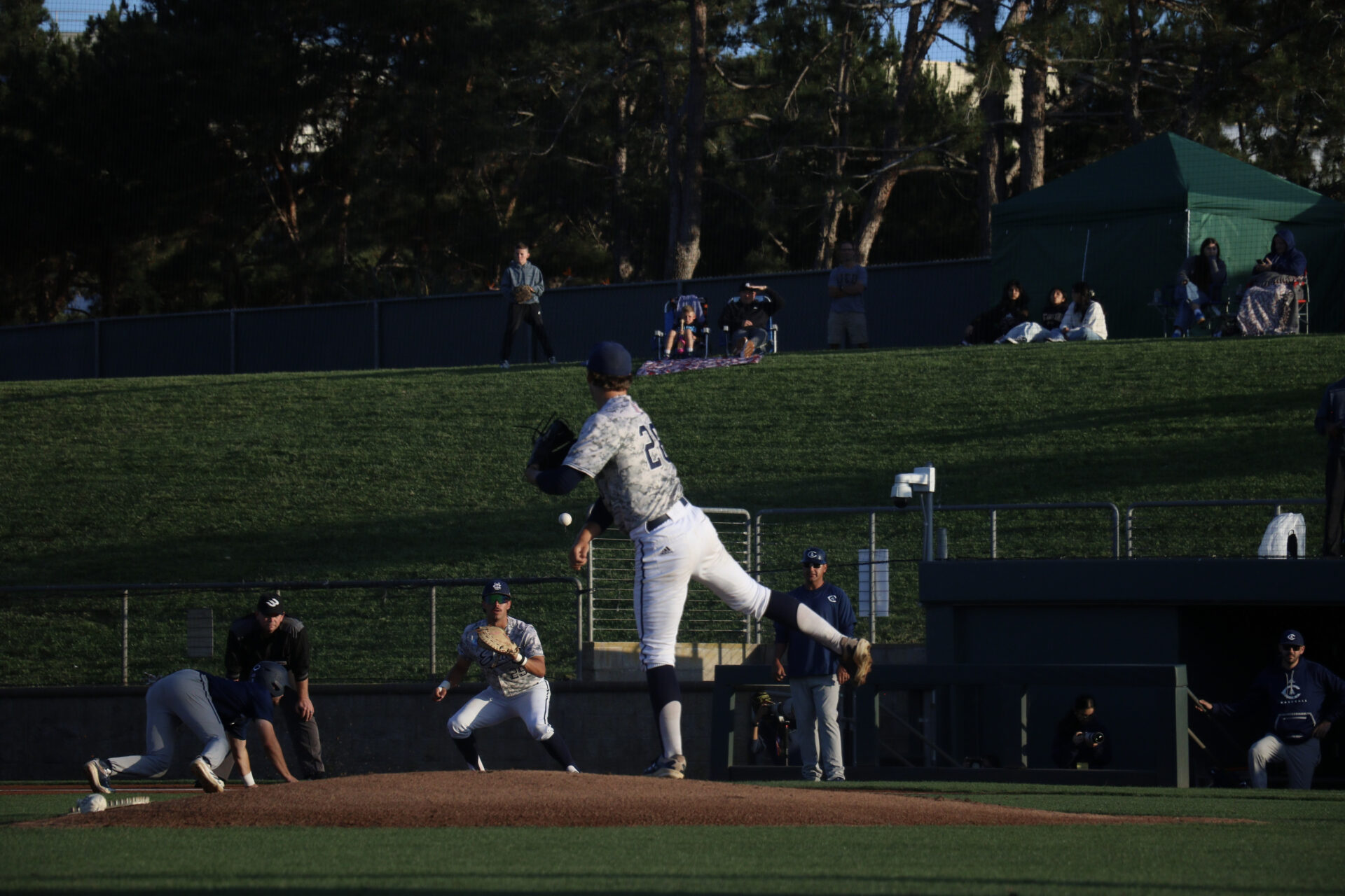 UC Irvine pitcher, number twenty eight, Trevor Hansen, throws a ball towards first base as Aggie player is on the floor after trying to steal second base.