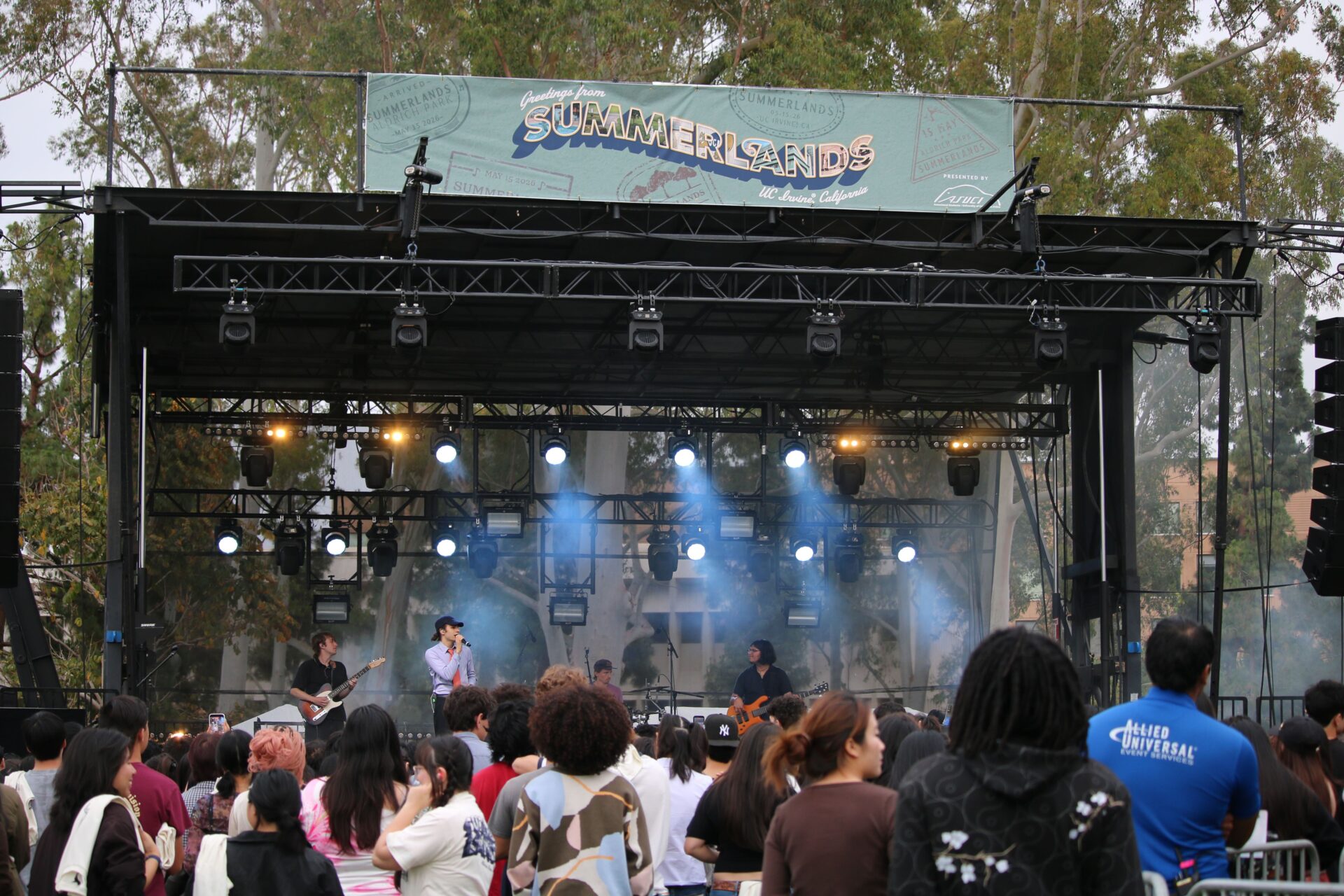 A crowd of students stand in front of a stage, where performers stand