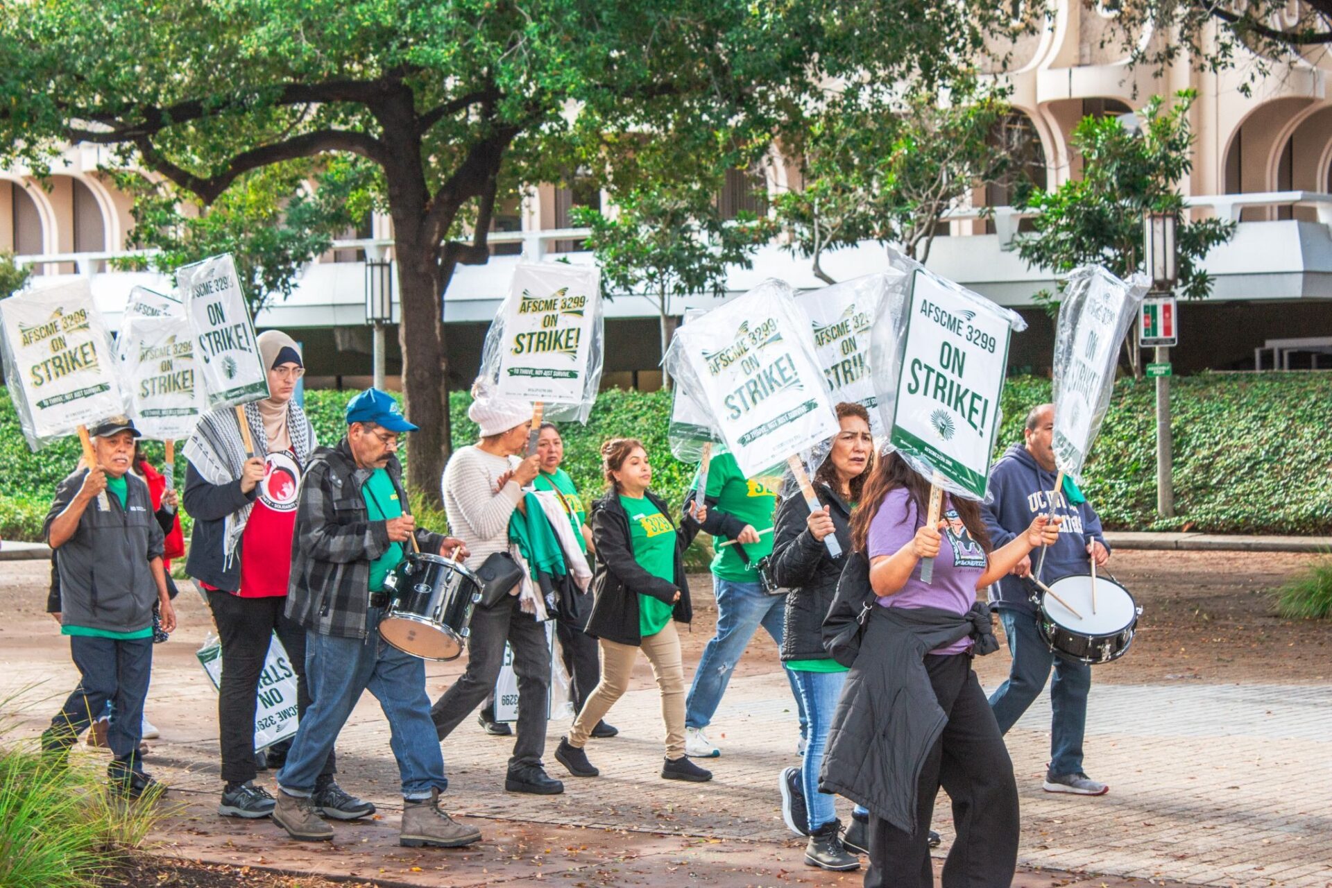 AFSCME Local 3299 members demonstrate next to Langson Library, carrying signs that read 