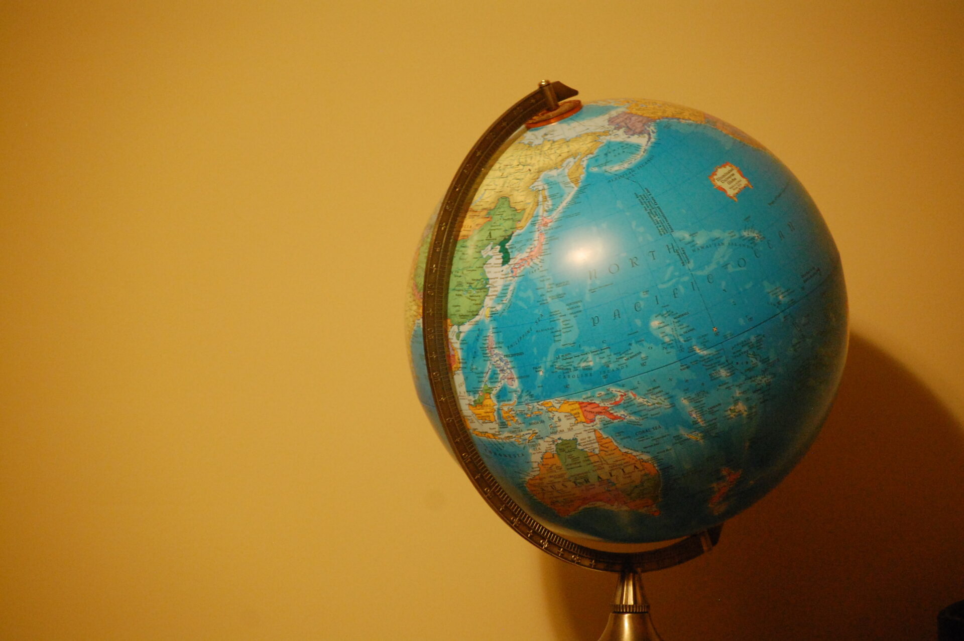 A model globe stands in front of a yellow background.