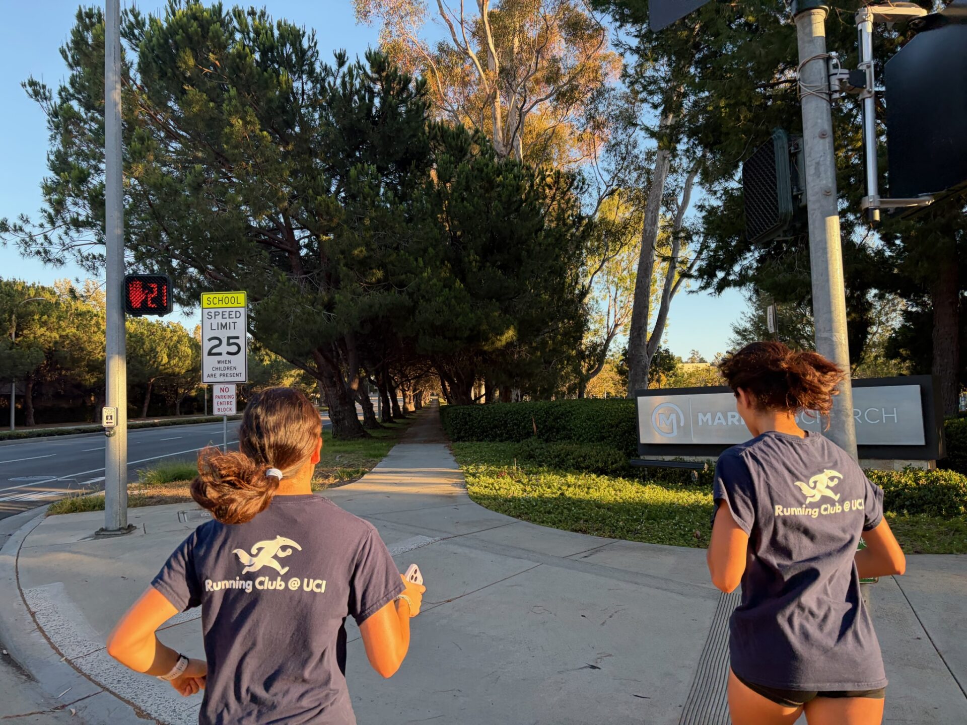 Two Running Club members run across an Irvine cross walk.