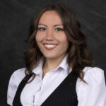 Kathryn Adalia Lehman in a button down white top and black vest.