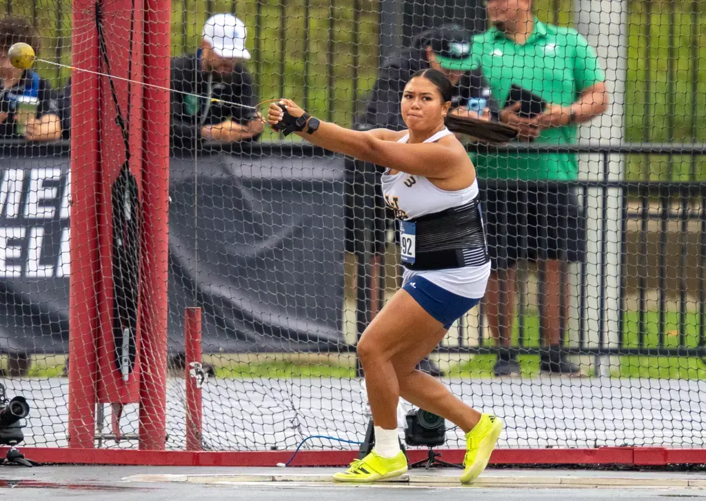 UC Irvine athlete prepares to throw the hammer in an enclosed area as coaches watch on