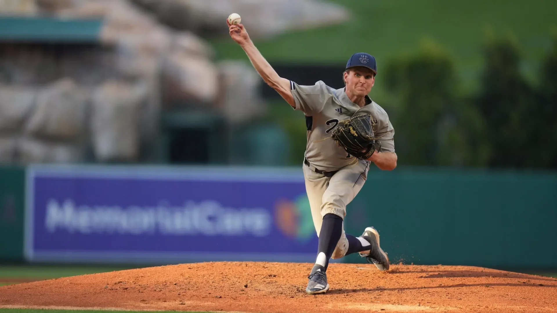 A right-handed pitcher hurls a pitch towards home plate, their face and right arm concentrated and tense.