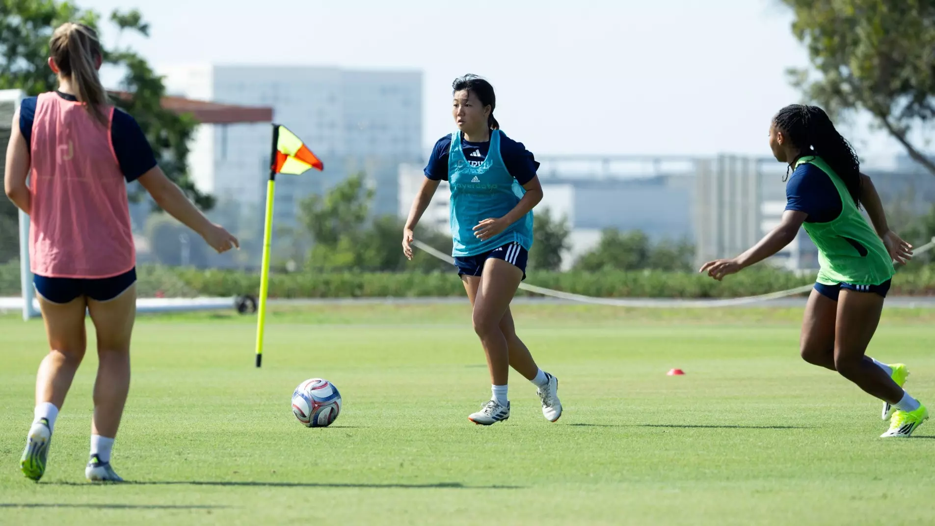 A women's soccer player eyes her next play against one player ahead of her and another to her left