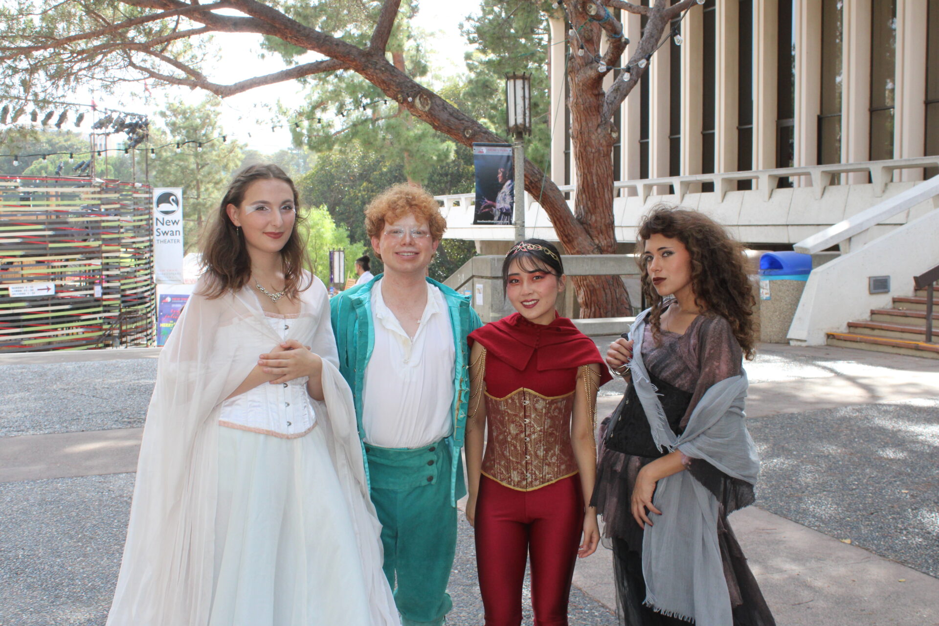 Four individuals dressed in costumes stand in front of a tree for the picture