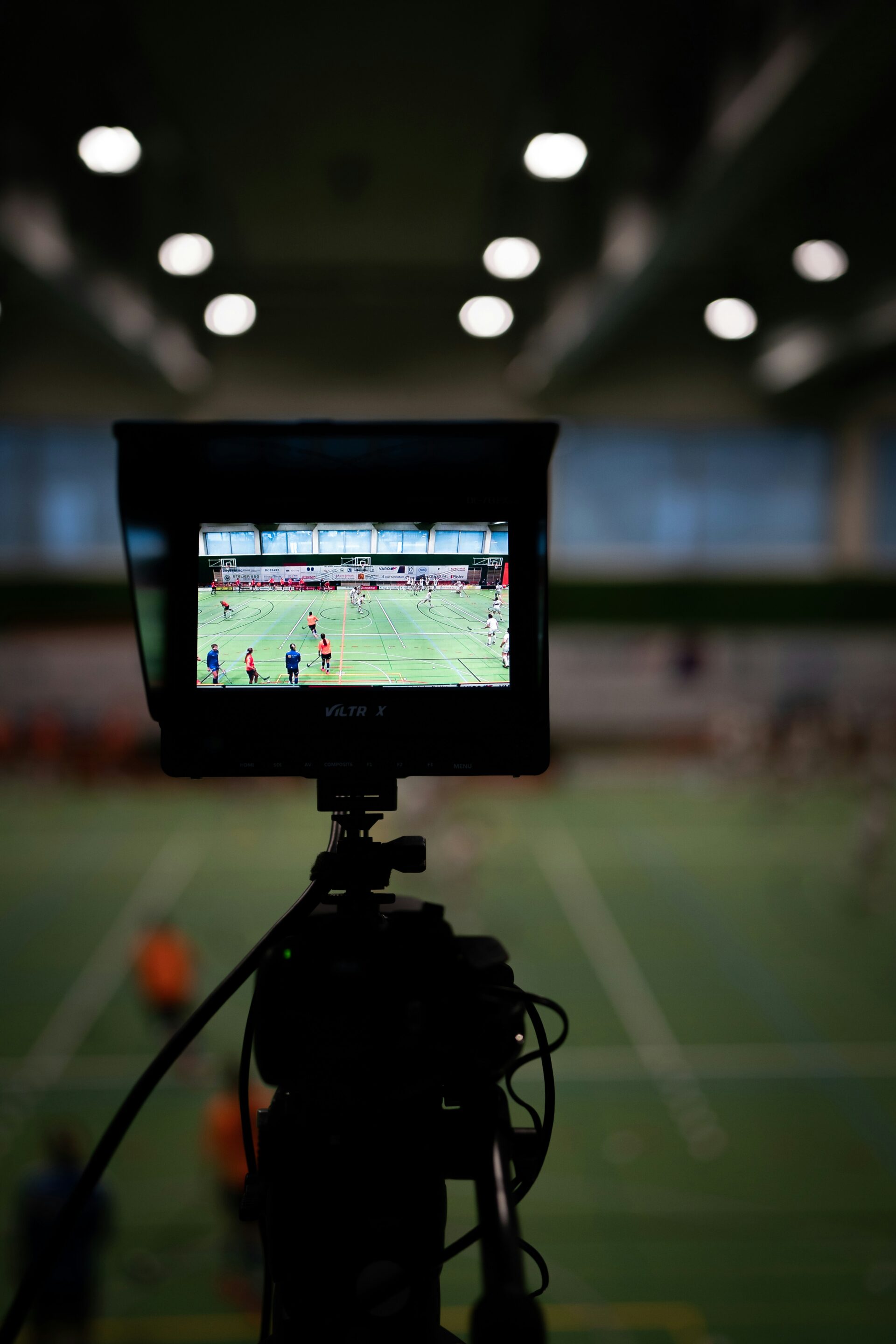 A camera points at a soccer field in the distance, while it's screen depicts players in the background