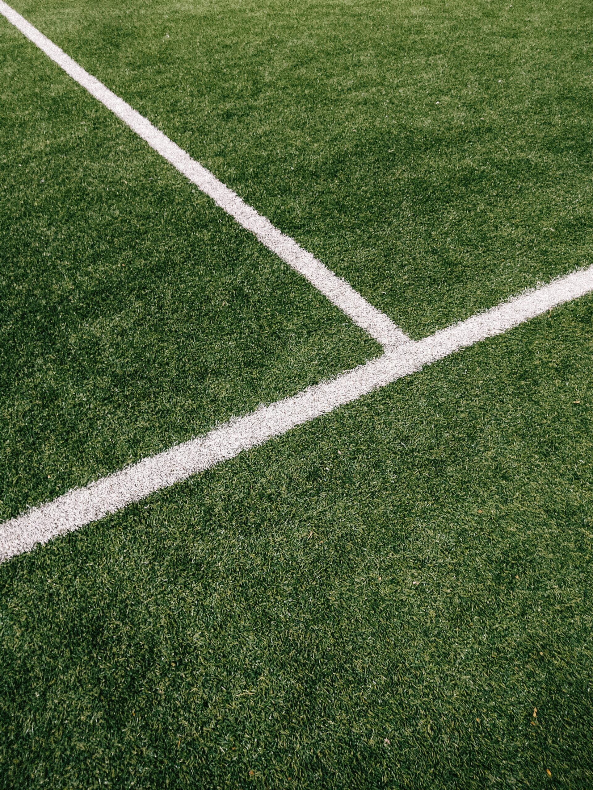 A white line runs horizontally across a patch of green field, while another white line connects and runs vertically.