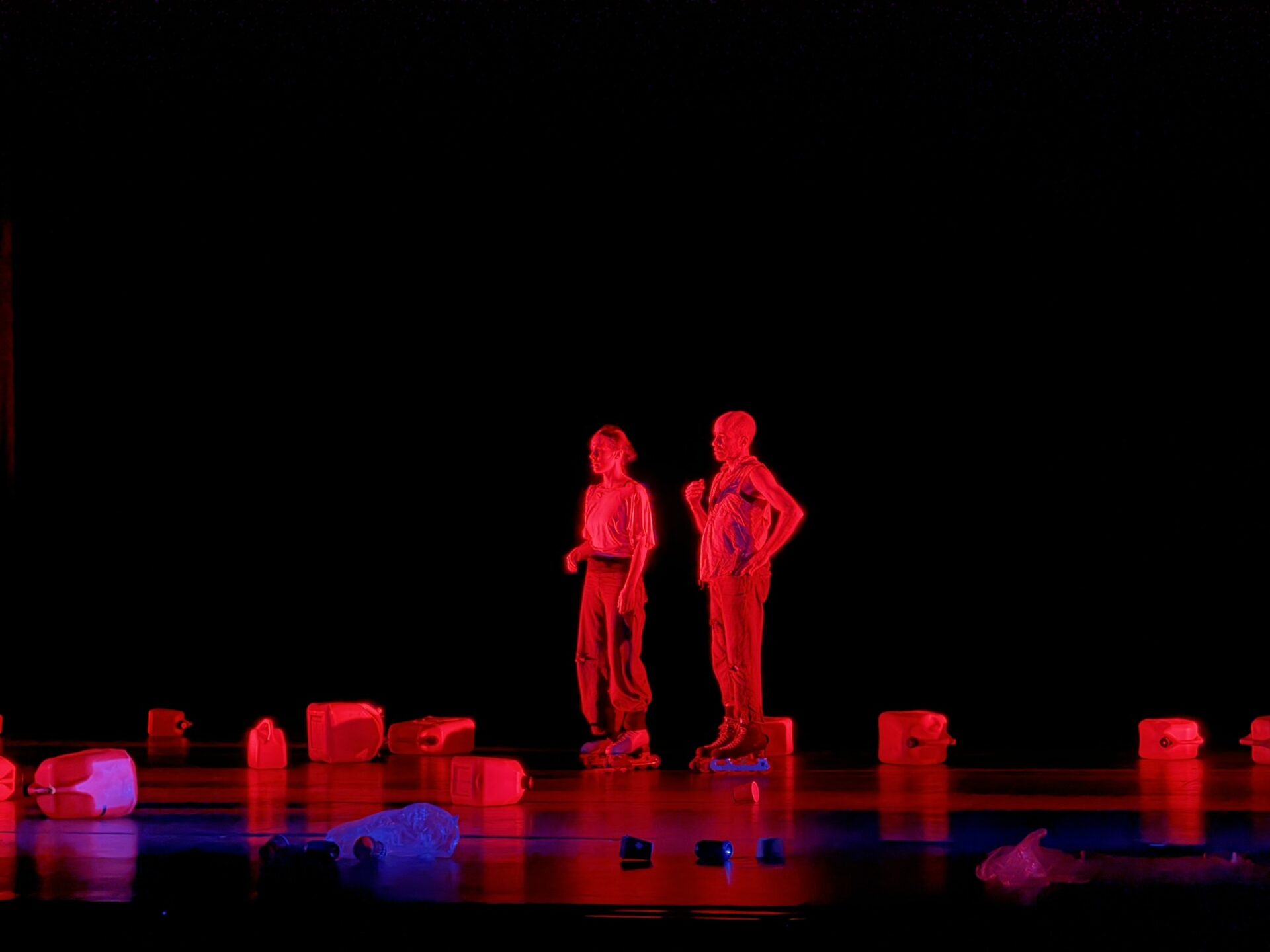 Two performers are lit by a red spotlight on the stage of the Barclay Theater.