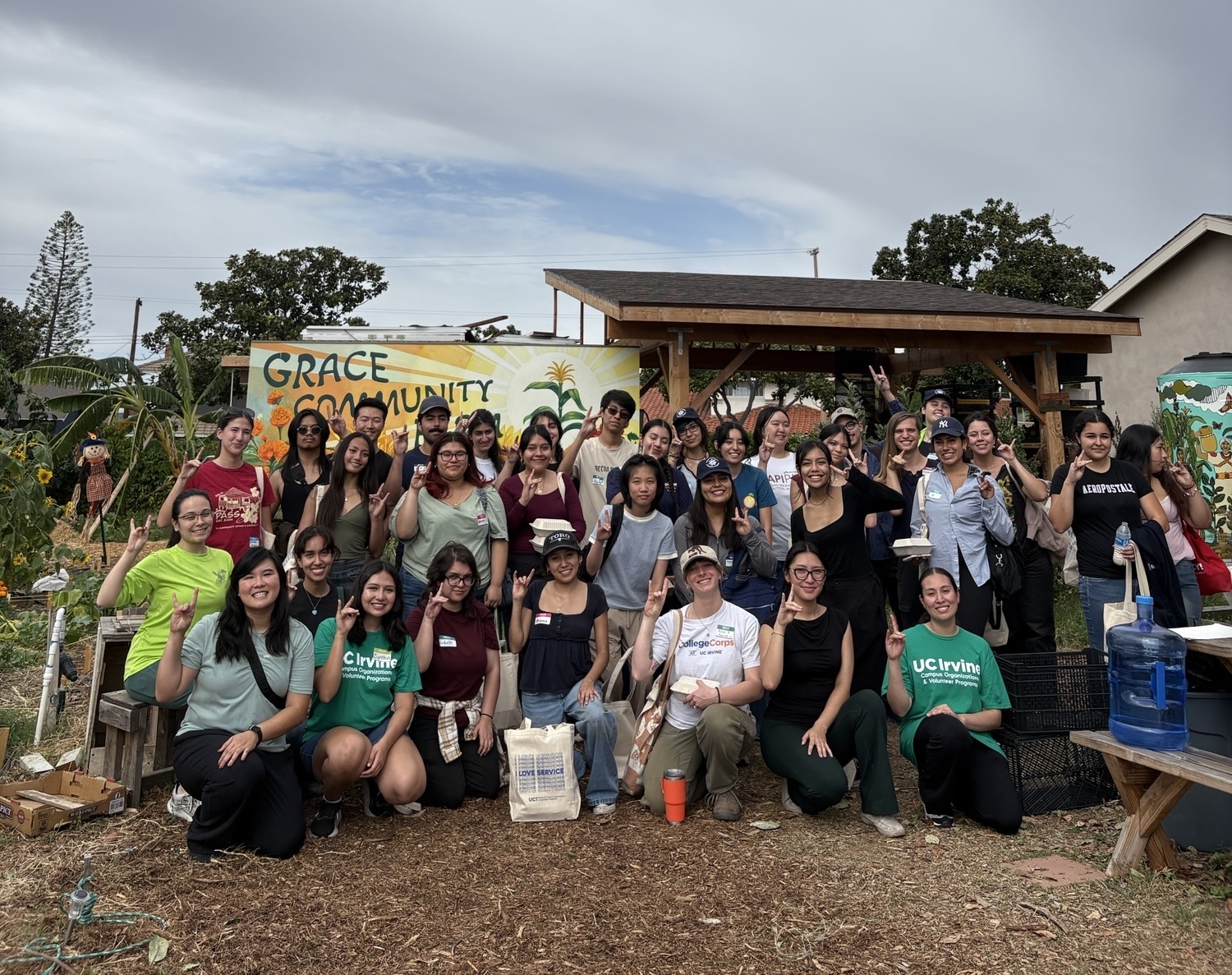 Three rows of participants at the Unity Through Service garden hold up a Zot in a group picture.