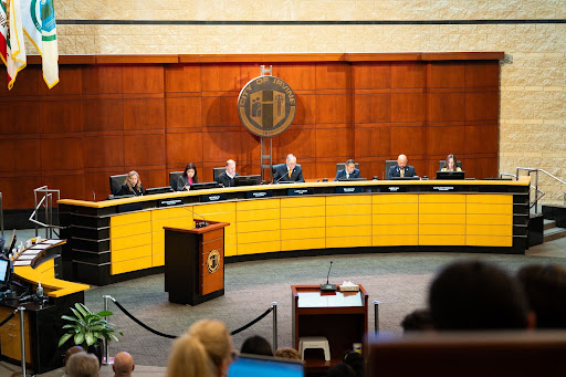 Wide view of council members seated during a public meeting. Photo caption: Irvine City Council members convene at City Hall on Oct. 13, 2026.